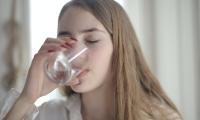 Ung pige der drikker vand af et glas