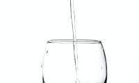 Tynd vandstråle der rammer ned i et glas